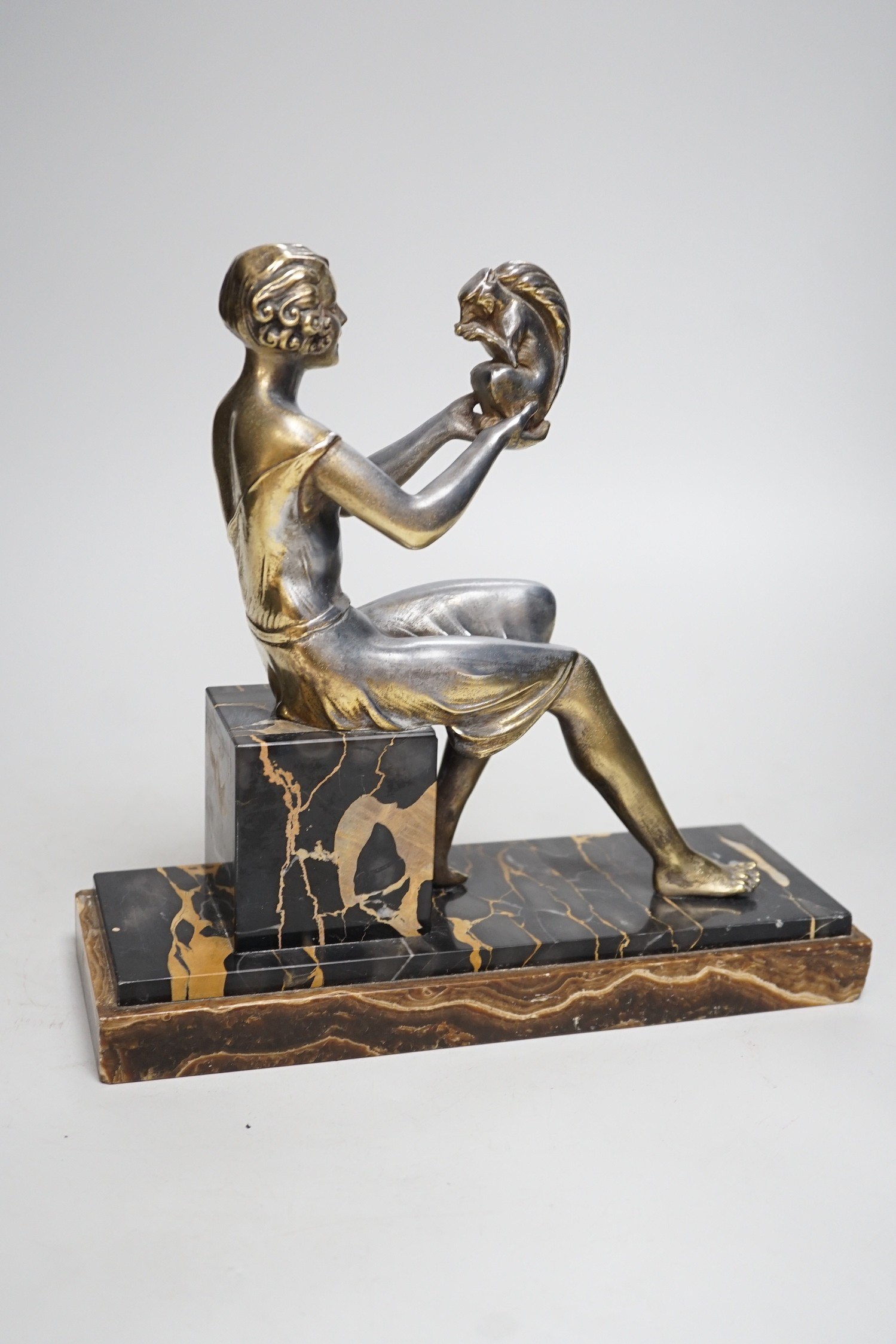 An Art Deco spelter gilded and silvered seated lady holding a squirrel, on marble and onyx mount, signed J. Dauvergne. 26cm tall